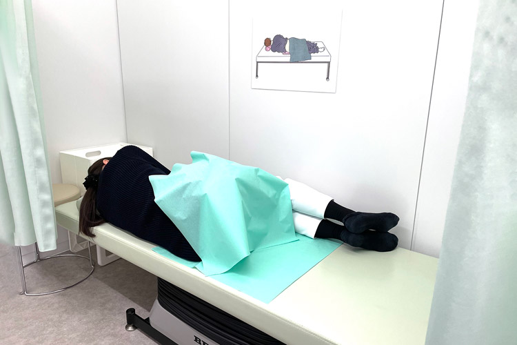 診察台の上で膝を抱えるような姿勢